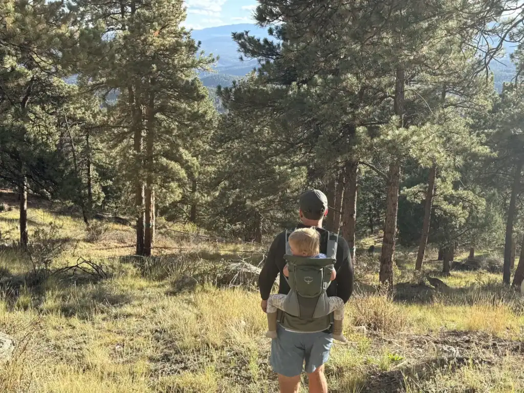 Dad standing on a forest trail with a toddler on his back in the Osprey Poco Soft child carrier