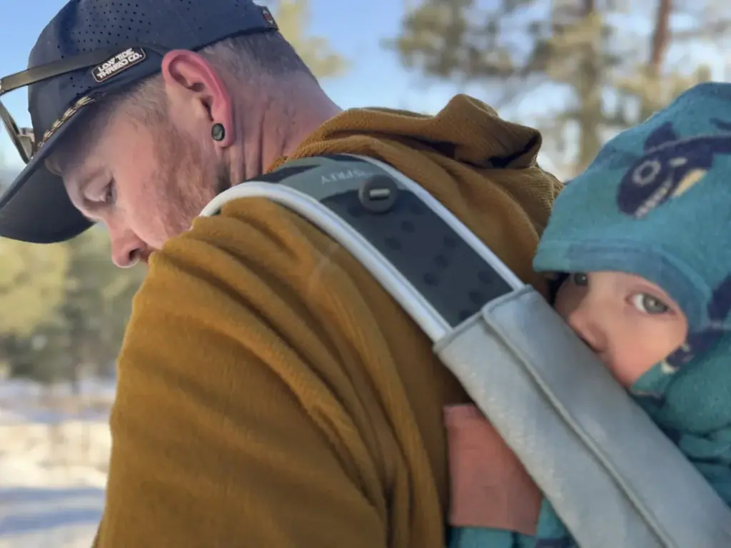 Dad carrying an infant face-in on the front in the Osprey Poco Soft child carrier