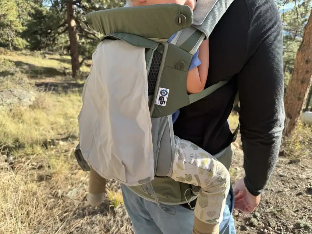 Sun hood pulled up over a toddler in the Osprey Poco Soft child carrier