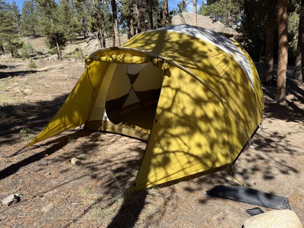REI Co-op Base Camp 6 with its vestibule door rolled back at a campsite