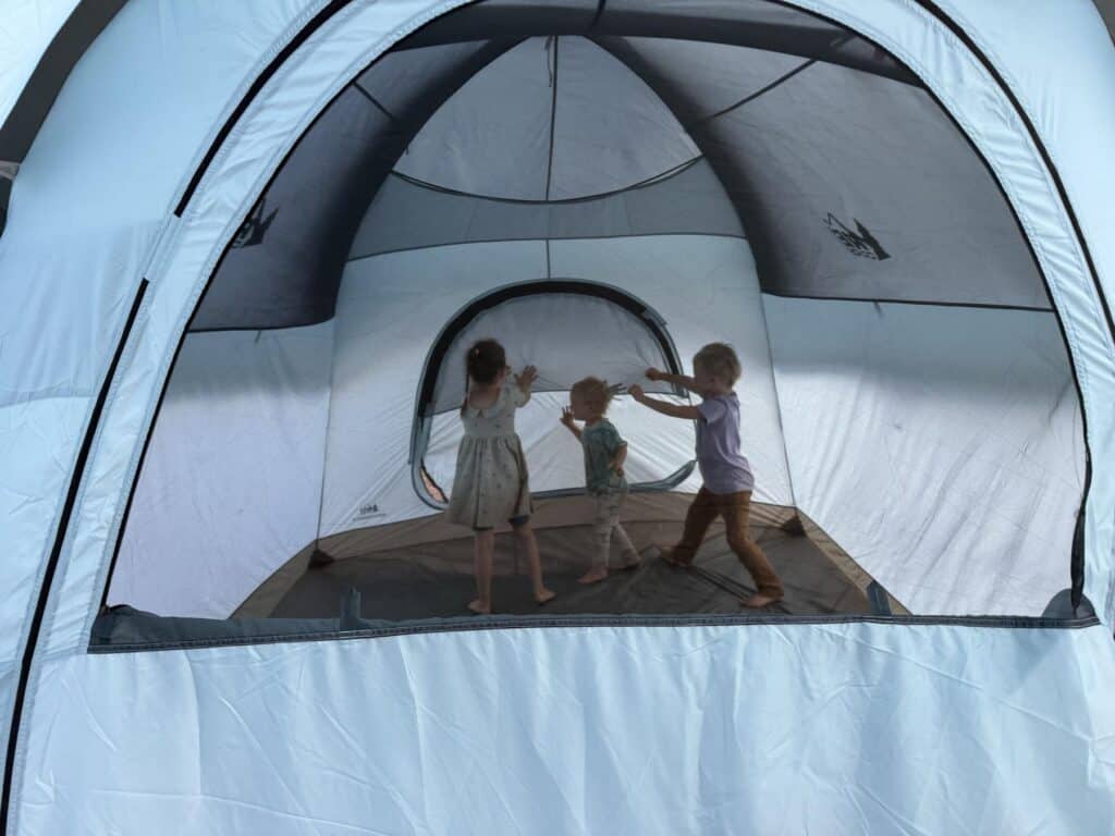 Three children playing inside the REI Co-op Westward 6, seen through the open door