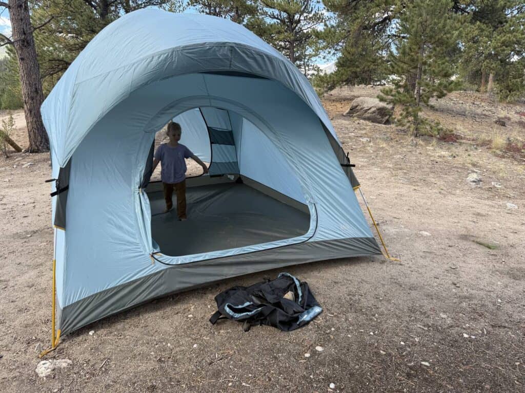 Child standing inside the REI Co-op Westward 6 tent body with the front door open and the rainfly off