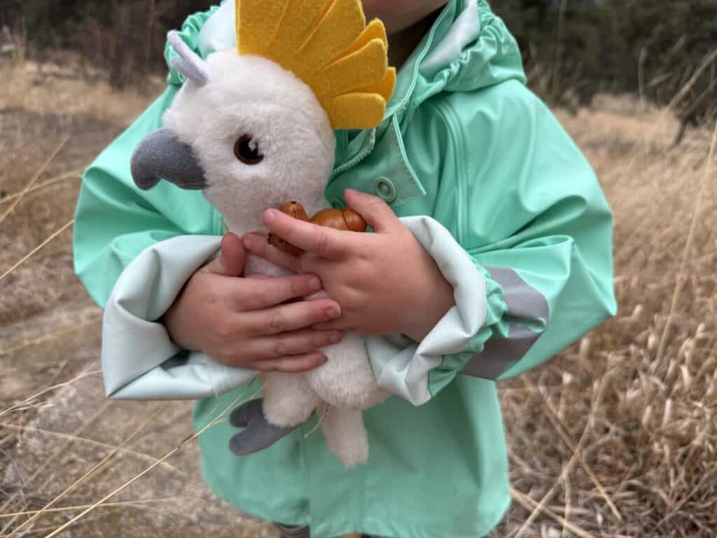 Toddler in yellow Reima Lampi Rain Jacket hugging a cockatoo, personality shot from testing