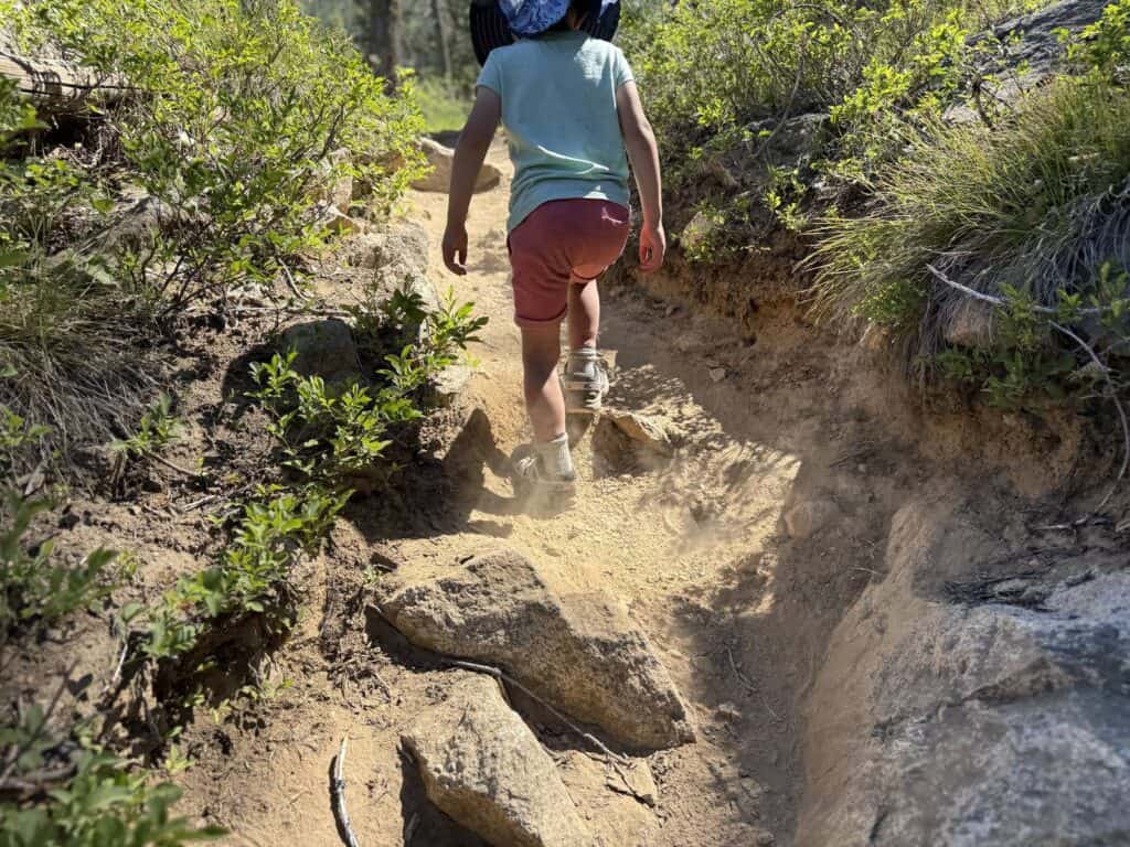 Kid climbing a steep dusty rock trail in Idaho wearing Salomon Speedcross shoes