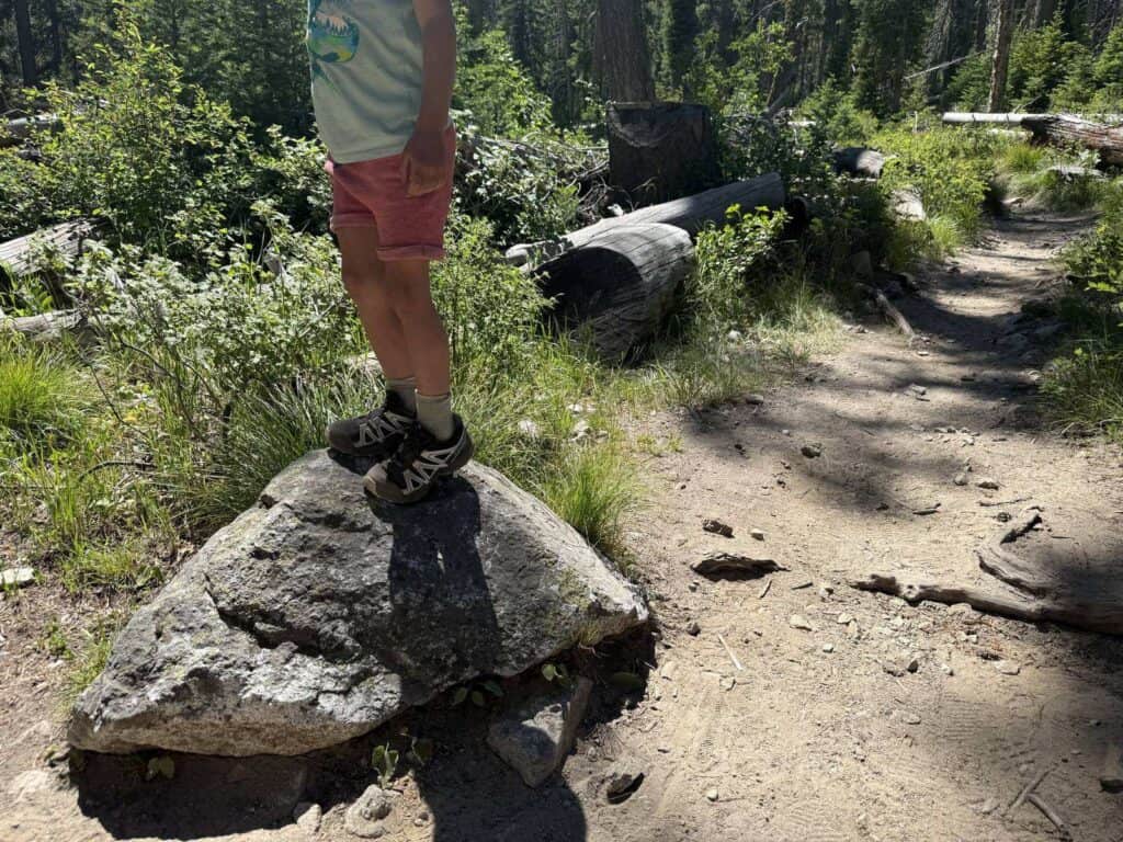 Kid standing on a rock beside a forest trail in Idaho in Salomon Speedcross shoes