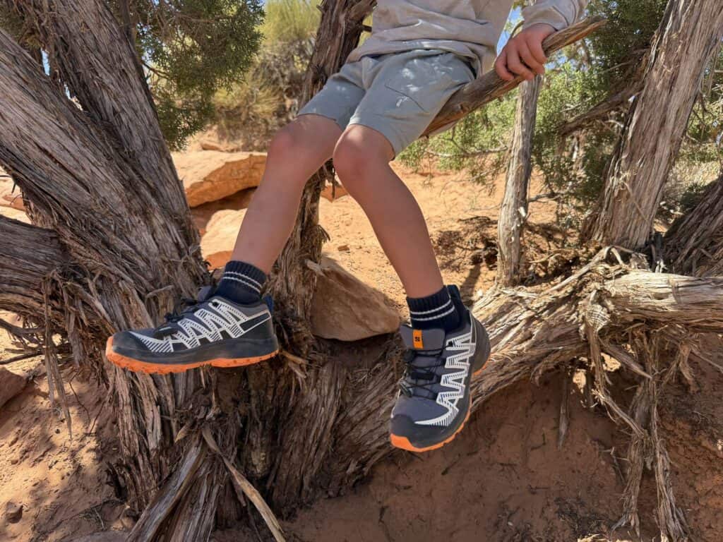 Kid climbing a juniper tree in Salomon XA Pro V8 Waterproof shoes, showing the outsole lugs