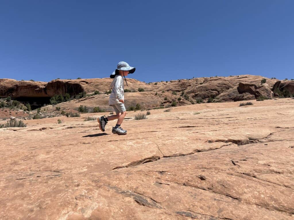 Kid in a sun hat hiking open slickrock in Arches National Park, Utah in Salomon XA Pro V8 Waterproof shoes