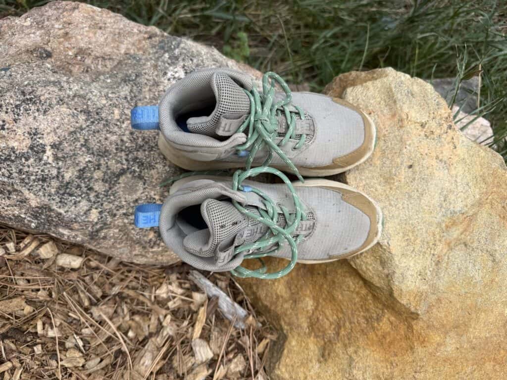 Pair of The North Face Fastpack II Mid Waterproof kids boots with green laces on a rock