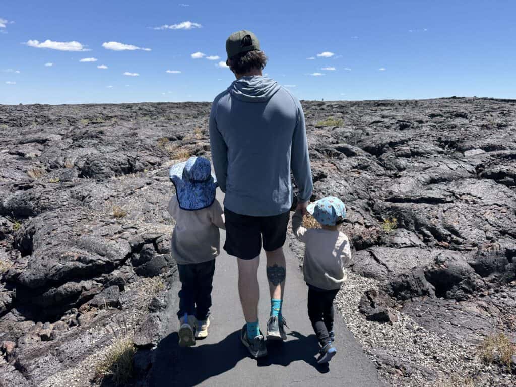 Adult and two kids walking a paved path through a lava field at Craters of the Moon, Idaho, one kid in The North Face Fastpack II Mid Waterproof boots