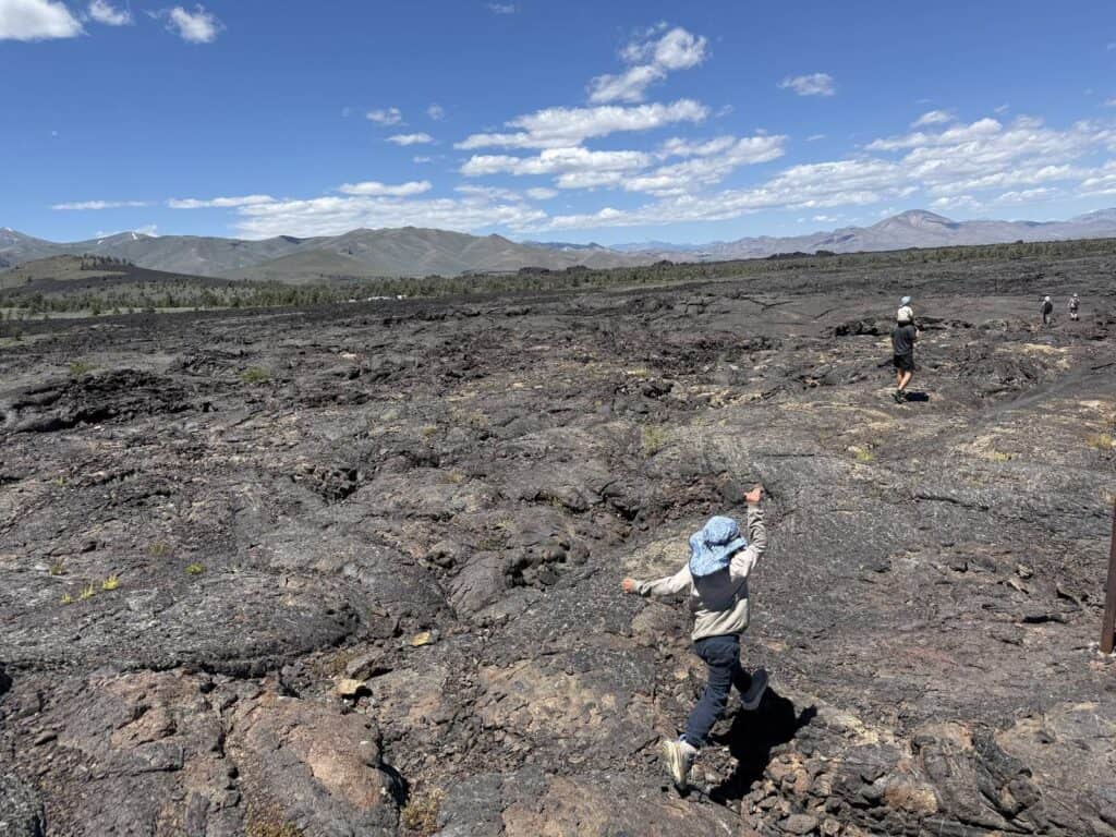 Kid hiking across a black lava field at Craters of the Moon, Idaho in The North Face Fastpack II Mid Waterproof boots