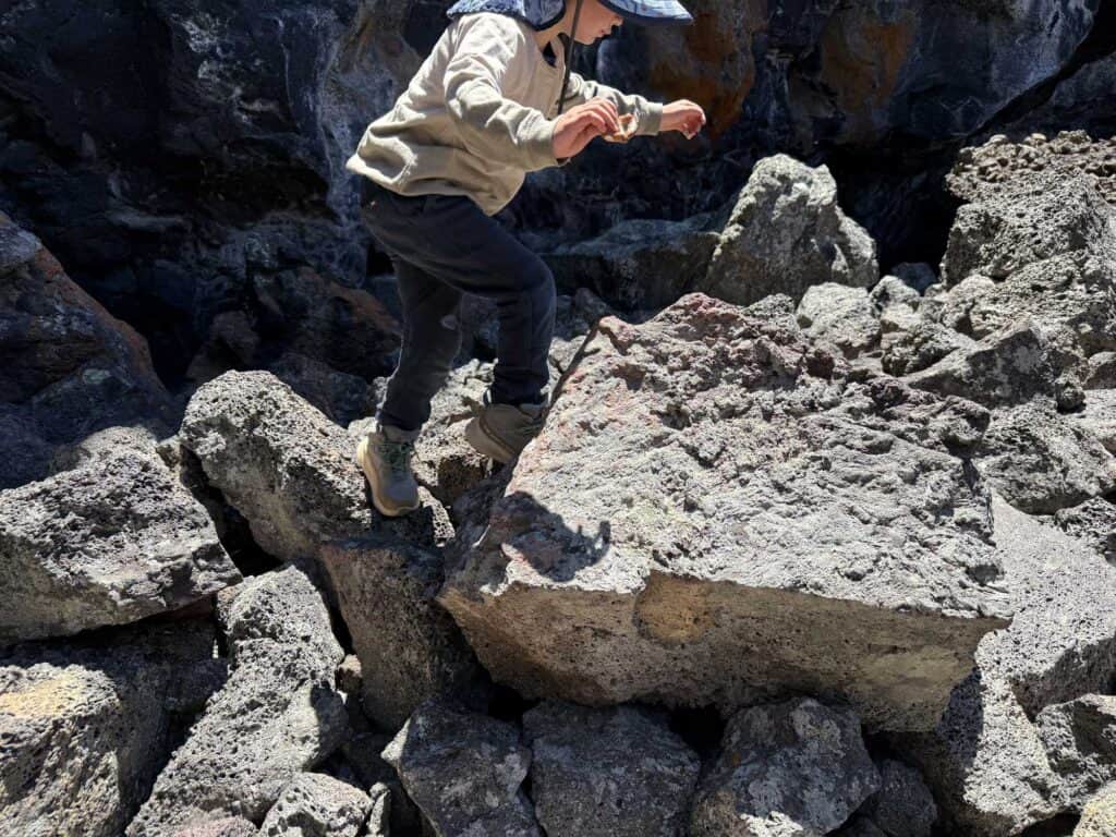 Kid scrambling over lava boulders at Craters of the Moon, Idaho in The North Face Fastpack II Mid Waterproof boots