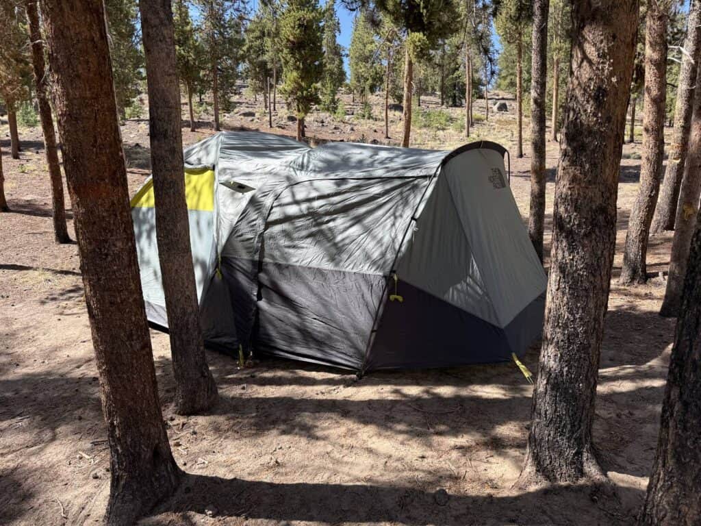 The North Face Wawona 6 pitched between pine trees on a dirt campsite