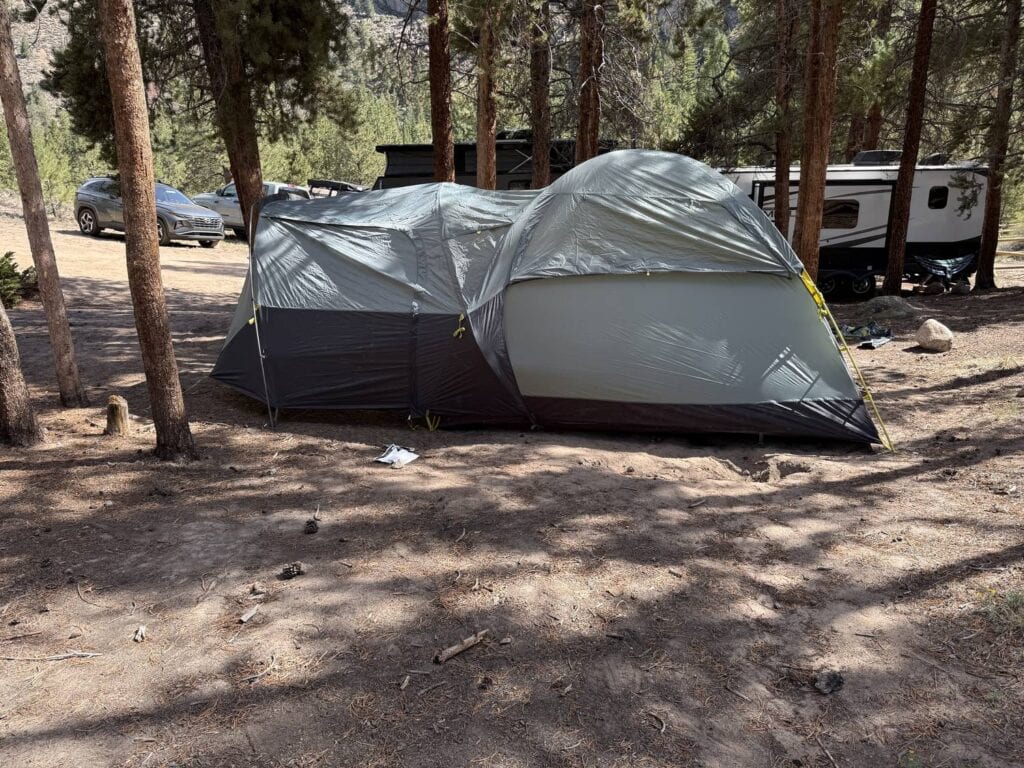 Side view of The North Face Wawona 6 with its partial rainfly at a campground with a car and camper behind it